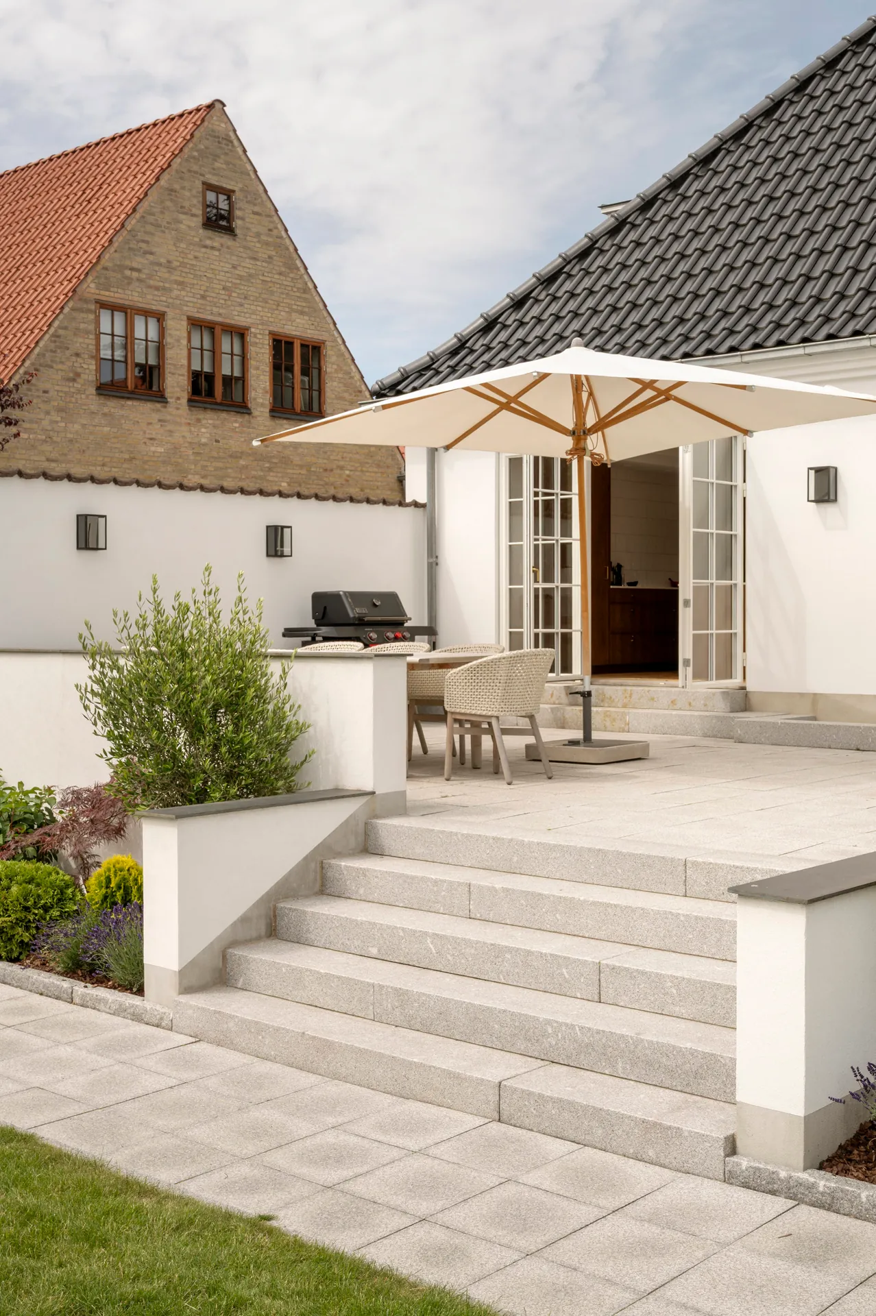 Trappe i granit op til terrasse med parasol ved hvid villa